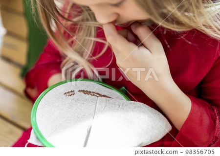 Close-up detail female child hands embroidering round hoop fabric frame with cross-stitch . Girl person handmade craft sewing pattern on canvas. Children development fine motor skills hobby artwork Close-up detail female child hands embroidering round hoop fabric frame with cross-stitch . Girl person handmade craft sewing pattern on canvas. Children development fine motor skills hobby artwork 98356705