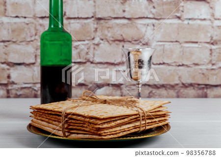 During Jewish holiday of Pesach cup of kosher kiddush wine is with unleavened bread called matzah soft focus 98356788