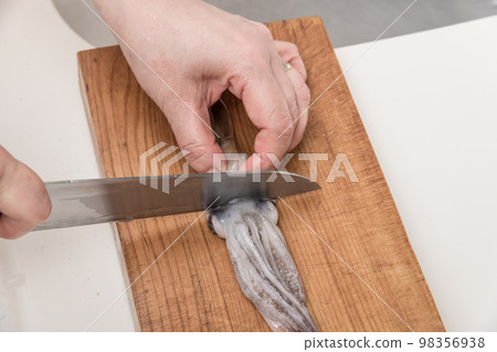 [A middle-aged housewife cuts a squid, preparing to remove her eyes] 98356938