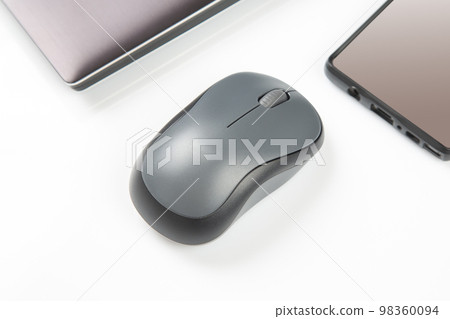Computer wireless mouse next to a laptop on a white table close-up. electronic personal industry 98360094