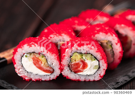 California sushi roll with salmon, avocado cucumber and tobiko caviar served on black board close-up - Japanese food 98360469