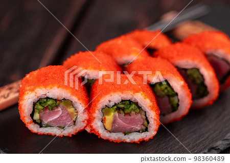 California sushi roll with tuna, avocado cucumber and tobiko caviar served on black board close-up - Japanese food California sushi roll with tuna, avocado cucumber and tobiko caviar served on black board close-up - Japanese food 98360489