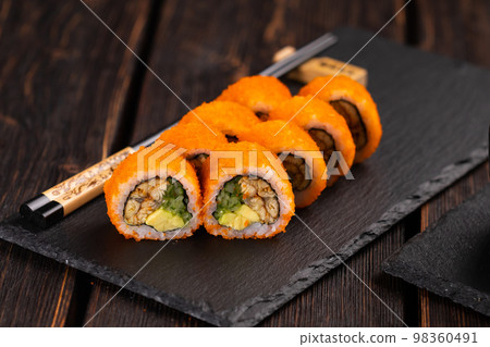 California sushi roll with eel, cucumber and tobiko caviar served on black board close-up - Japanese food 98360491