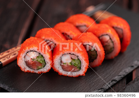 California sushi roll with salmon crab, cucumber and tobiko caviar served on black board close-up - Japanese food California sushi roll with salmon crab, cucumber and tobiko caviar served on black board close-up - Japanese food 98360496