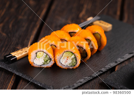California sushi roll with crab, avocado, cucumber and tobiko caviar served on black board close-up - Japanese food California sushi roll with crab, avocado, cucumber and tobiko caviar served on black board close-up - Japanese food 98360500