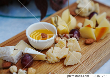 wooden tray with cheese cuts, nuts, grapes and honey. wooden tray with cheese cuts, nuts, grapes and honey. 98361258