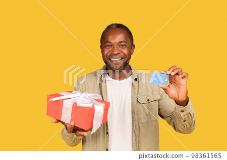 Cheerful african american middle aged man show gift box and credit card, recommend banking 98361565
