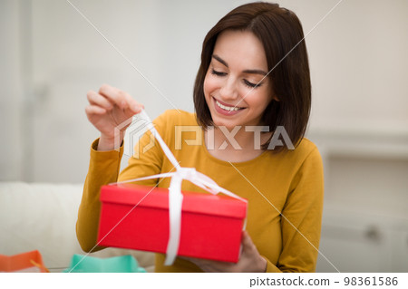 Happy young woman sit on couch unpack cardboard box Happy young woman sit on couch unpack cardboard box 98361586