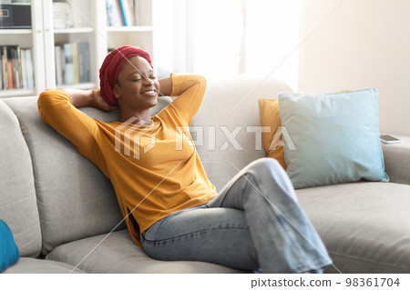 Relaxed black lady resting on couch at home 98361704