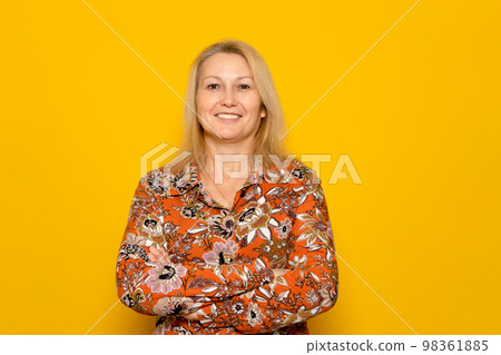 Pretty caucasian blonde woman posing smiling with arms crossed isolated on orange studio background. Pretty caucasian blonde woman posing smiling with arms crossed isolated on orange studio background. 98361885