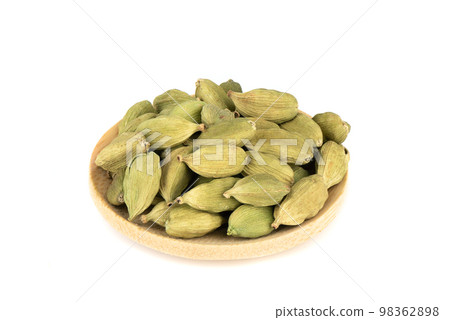 Wooden mini plate with green cardamom pods over white background. Wooden mini plate with green cardamom pods over white background. 98362898