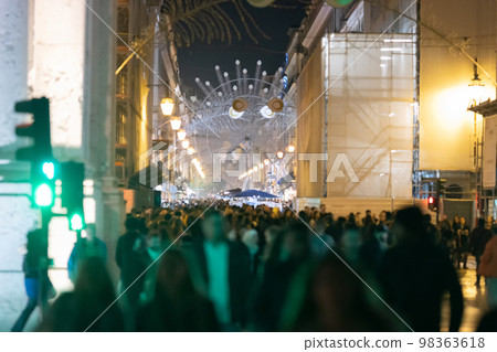 People crowd on a European street decorated for Christmas 98363618