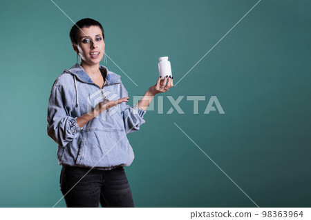 Portrait of woman holding pills bottle showing at camera after receiving treatment recovery on prescription. Smiling adult reviewing pharmaceutical supplement, healthy lifestyle concept 98363964