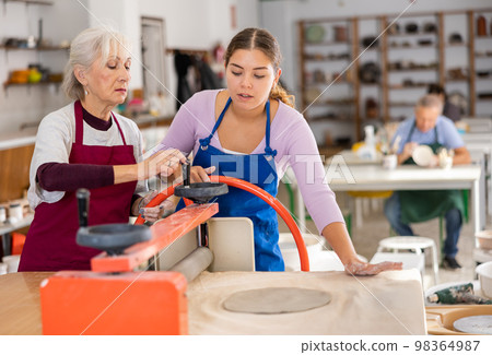 women in pottery workshop work with roller press 98364987