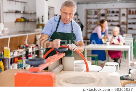 male potter works with machine clay press roller 98365027