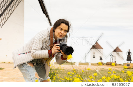 Tourist with camera in front of the windmills of the Mota del cuervo. Spain 98365067