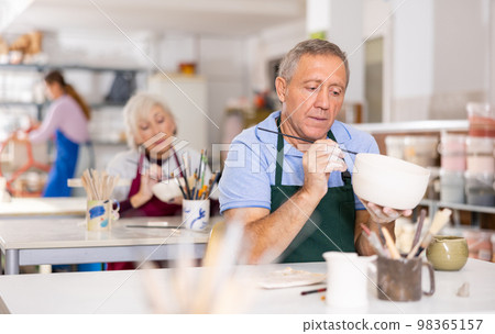 man potter carefully paints vase 98365157