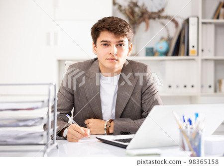 Male worker engaged in business activities at workplace in office 98365158