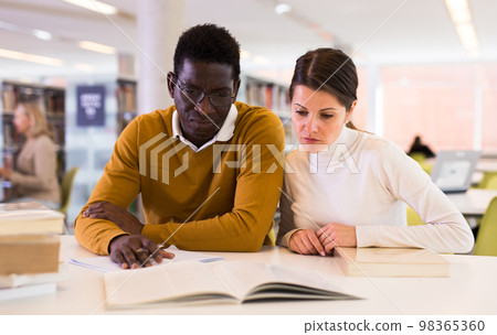 People reading and making notes while preparing for exam in library People reading and making notes while preparing for exam in library 98365360
