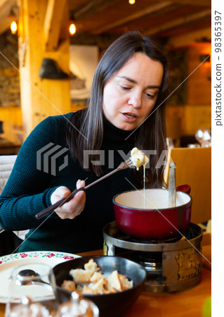 Woman eating tradicional Swiss dish - fondue 98365397