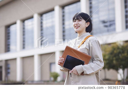 A young Japanese female university student heads to class with her tablet in hand. A young Japanese female university student heads to class with her tablet in hand. 98365778