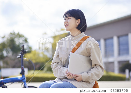 A young Japanese female university student heading to class with her laptop. A young Japanese female university student heading to class with her laptop. 98365796