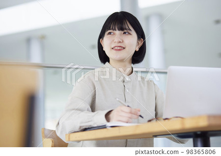 A young Japanese woman carrying a study laptop on campus. A young Japanese woman carrying a study laptop on campus. 98365806
