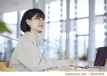 A young Japanese woman carrying a laptop and a bag on campus. A young Japanese woman carrying a laptop and a bag on campus. 98365808