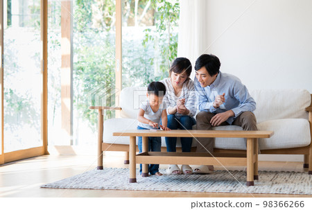 一個年輕的家庭在客廳裡看智能手機 一個年輕的家庭在客廳裡看智能手機 98366266