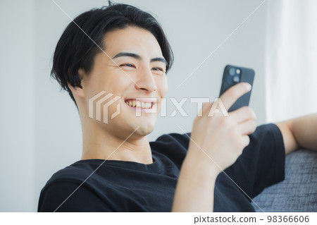 A man seeing a smartphone on a sofa A man seeing a smartphone on a sofa 98366606