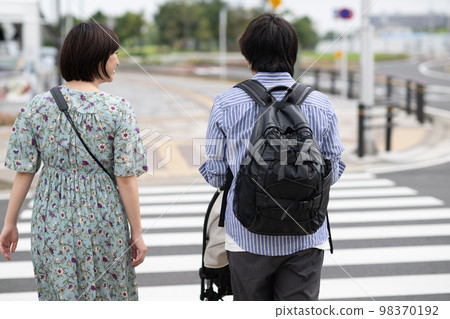 A couple raising children crossing a pedestrian crossing 98370192