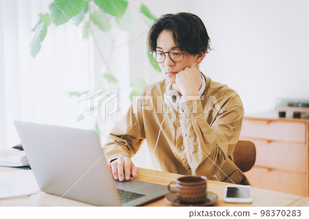 A man who uses a personal computer at home A man who uses a personal computer at home 98370283