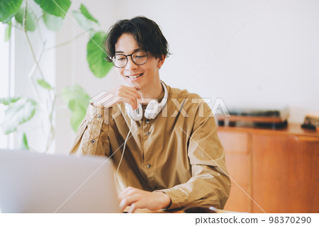 A man who uses a personal computer at home 98370290