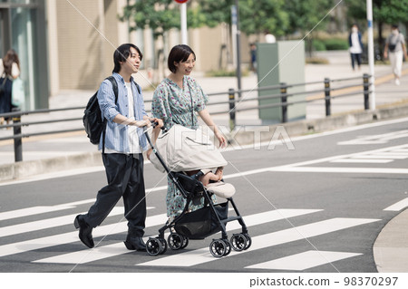 A couple raising children crossing a pedestrian crossing A couple raising children crossing a pedestrian crossing 98370297