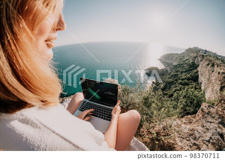 Woman sea laptop. Business woman working on laptop by sea at sunset. Close up on hands of pretty lady typing on computer outdoors summer day. Freelance, digital nomad, travel and holidays concept. 98370711
