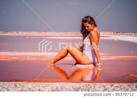 Young woman with long hair in pink salty lake with crystals of salt. Extremely salty pink lake, colored by microalgae with crystalline salt depositions. Spa, beauty and health care concept. 98370712
