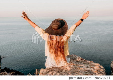 Portrait of happy young woman wearing summer black hat with large brim at beach on sunset. Sensual girl covering half face with hat on beach. Happy young woman smiling and looking at camera at sea. Portrait of happy young woman wearing summer black hat with large brim at beach on sunset. Sensual girl covering half face with hat on beach. Happy young woman smiling and looking at camera at sea. 98370741