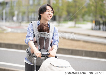 A man who is raising children walking in the city 98370779