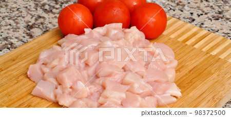 Fresh uncooked chicken meat breast pieces, ready to cook, with tomato Fresh uncooked chicken meat breast pieces, ready to cook, with tomato 98372500