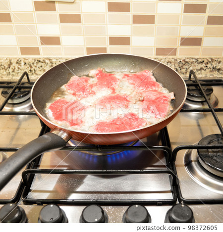 Fresh red cow tenderloin frying in pan on stove, homemade food Fresh red cow tenderloin frying in pan on stove, homemade food 98372605