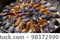 Macro caramelized in sugar syrup pieces of plums in round baking dish on wooden table 98372990