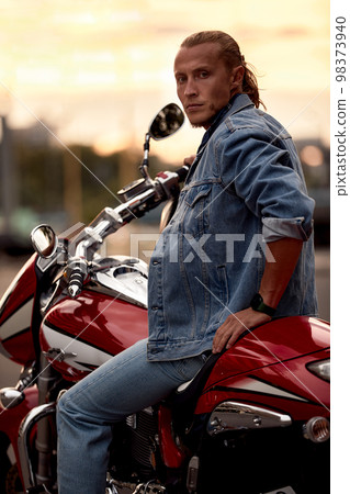 Biker rides a motorcycle in an urban landscape. 98373940