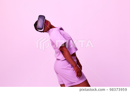 A cheerful girl in virtual reality glasses. Blue and purple colors. A cheerful girl in virtual reality glasses. Blue and purple colors. 98373959