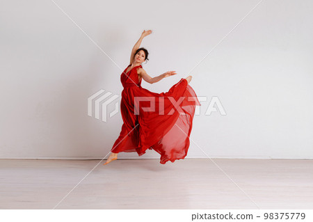 Dancer in a red flying dress. Woman ballerina dancing on a white studio background Dancer in a red flying dress. Woman ballerina dancing on a white studio background 98375779