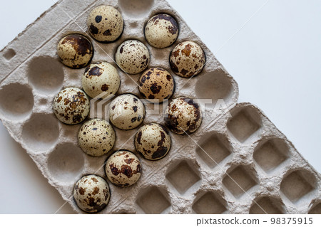 Spotted quail eggs in an egg box on a light background, natural eco-friendly products. 98375915