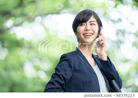 A business woman in a suit talking on a smartphone A business woman in a suit talking on a smartphone 98376223