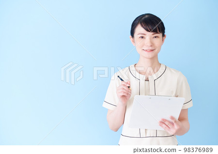 A woman at an esthetic and beauty clinic writing a chart 98376989