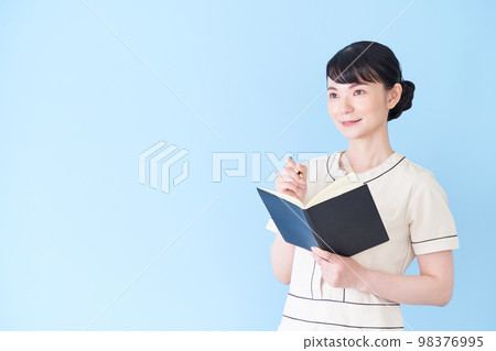A woman at an esthetic and beauty clinic writing a notebook 98376995