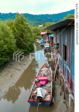 Fishermen's village in Asia. Boats near dilapidated houses on stilts. 98377474