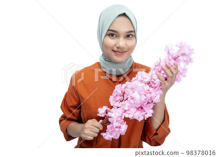 Asian Muslim woman in a headscarf holding a pink flower Asian Muslim woman in a headscarf holding a pink flower 98378016